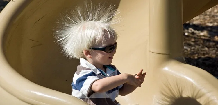 Static electricity from this plastic slide causes the child's hair to stand on end. The sliding motion stripped electrons away from the child's body, leaving an excess of positive charges, which repel each other along each strand of hair.