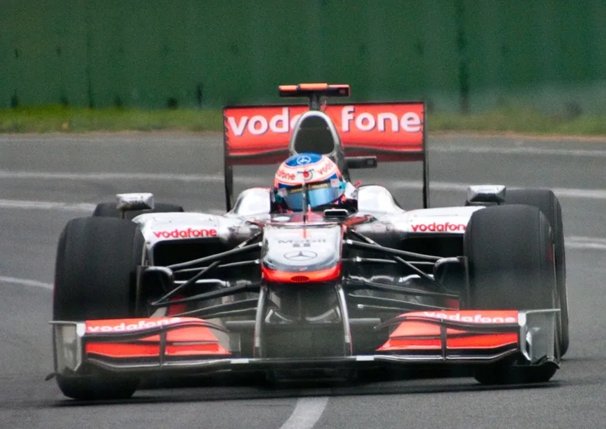 This Australian Grand Prix Formula 1 race car moves in a circular path as it makes the turn. Its wheels also spin rapidly—the latter completing many revolutions, the former only part of one (a circular arc). The same physical principles are involved in each.